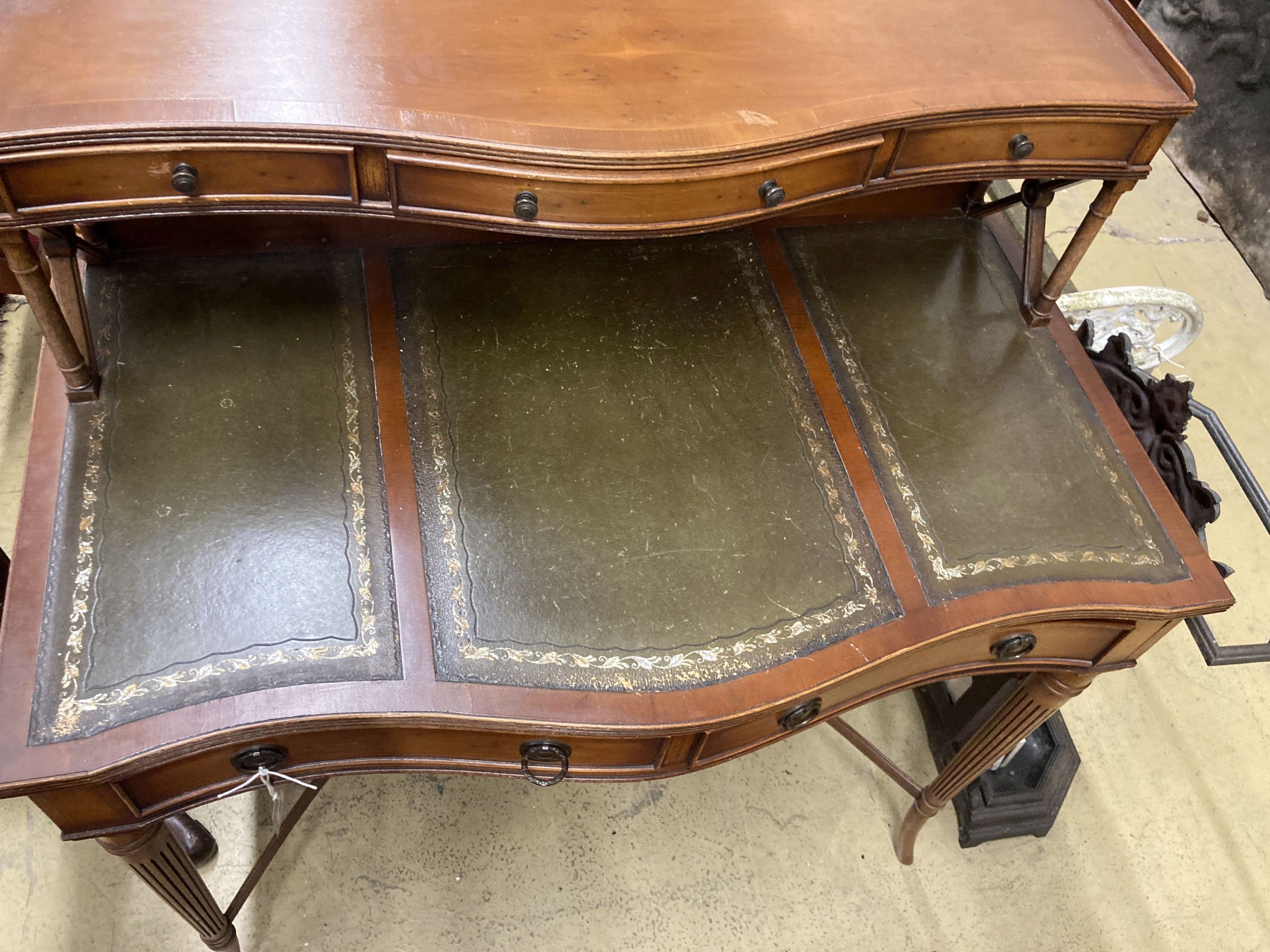 A reproduction yew serpentine writing table, width 92cm, depth 50cm, height 103cm